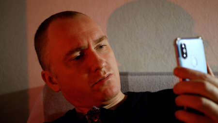 A young man with a serious look. Frowning man in red tones evil smile.の写真素材