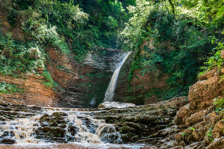 water falls from a cliff and flows beautifully over the rocks. Waterfall Maiden spit, Adygea, Russiaの写真素材
