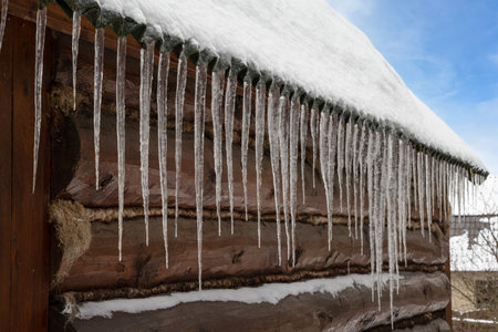 Sharp and transparent icicles hung from the roof of the village log house. close-up photoの写真素材