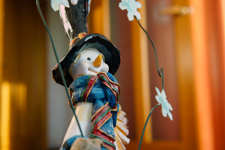 Vintage toy snowman figurine on wooden background in black top-hat with colorful scarfの写真素材
