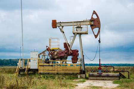 Pump jack with a derrick drilling a new well in the background.の写真素材