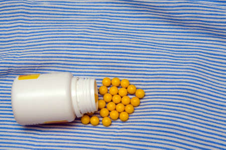 yellow pills and pill bottle on blue backgroundの写真素材