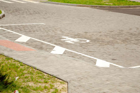 empty handicapped parking lot on a street - legs of bypasser on pavementの写真素材