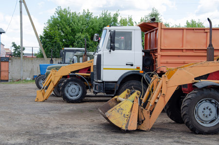 Multiple cars, trucks, loaders, concrete mixers and construction machinery in large parking lot in...