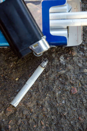 with lighter and cigarette on dark asphalt backgroundの写真素材