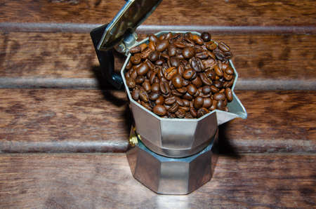 Coffee in a moka pot with coffee beans and ground coffee on blur dark background. Preparing fresh traditional italian espresso coffee.の写真素材