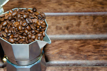 Coffee in a moka pot with coffee beans and ground coffee on blur dark background. Preparing fresh traditional italian espresso coffee.の写真素材