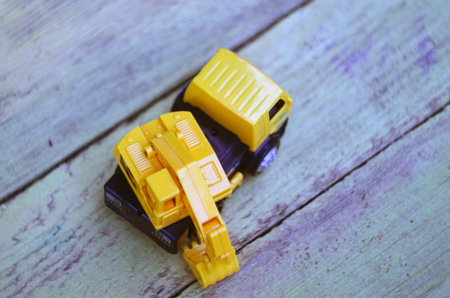 Yellow plastic excavator in the sand. Toy construction equipment. Childrens toys on the beach.