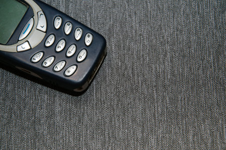 An old mobile phone on a rag-gray background.