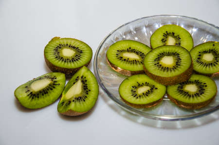 Slices of gold kiwi on glass plate white backgroundの写真素材