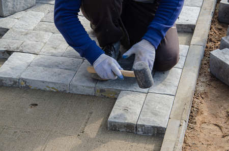 Construction of pavement near the house. Bricklayer places concrete paving stone blocks for building up a Sidewalk pavementの写真素材