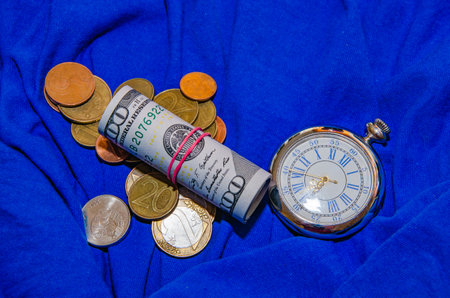 100 dollar bills twisted into a tube isolated on blue background.の写真素材