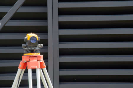 Surveying measuring equipment level transit on tripod at construction buildingの写真素材