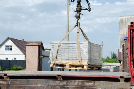 Unloading paving slabs from a truck. Men unload paving slabs using a manipulator.の写真素材
