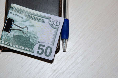 Top view mockup of open blank notebook on spiral, automatic pen and 50 dollar banknotes on a wooden tableの写真素材