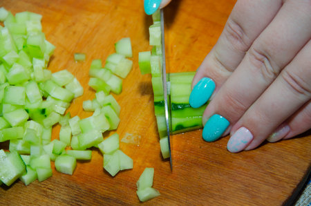 Finely chopping an organic seedless cucumber on a bamboo cutting boardの写真素材