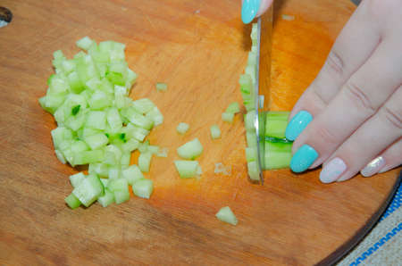 Finely chopping an organic seedless cucumber on a bamboo cutting boardの写真素材