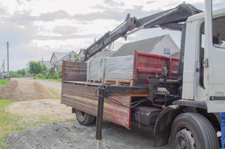 Loading a pallet with paving slabs on a truck. Loading tiles to the ground from a car. Delivery and...