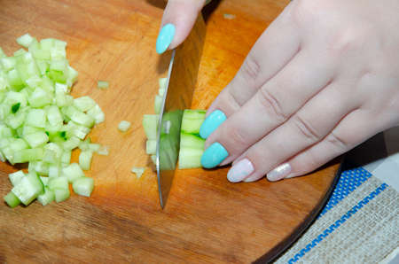 Dicing an English Cucumber with a Santoku Knife: Finely chopping an organic seedless cucumber on a bamboo cutting boardの写真素材