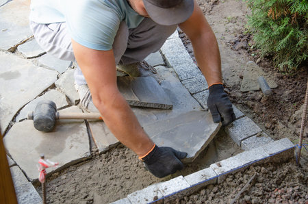 Construction of pavement near the house. Bricklayer places concrete paving stone blocks for building up a Sidewalk pavementの写真素材