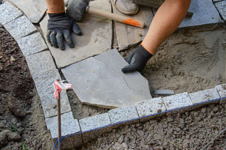 Construction of pavement near the house. Bricklayer places concrete paving stone blocks for building up a Sidewalk pavementの写真素材