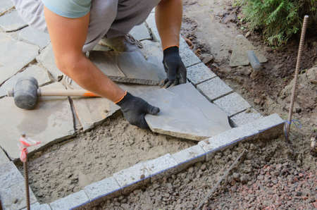 Construction of pavement near the house. Bricklayer places concrete paving stone blocks for building up aの写真素材