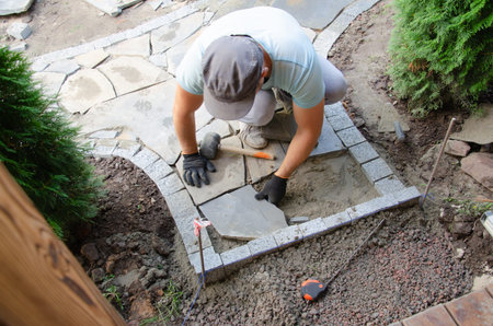 Construction of pavement near the house. Bricklayer places concrete paving stone blocks for building up aの写真素材