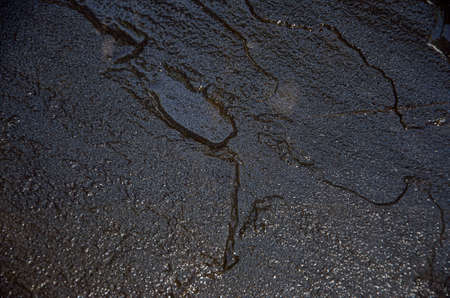 Dark stone wall shining with the light and giving the reflection wet appearance wetの写真素材