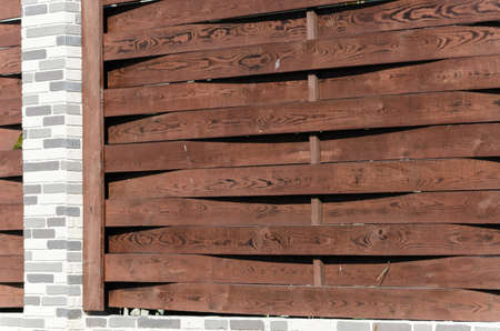 Decorative concrete orange fence with brick posts near a residential building with a garden.の写真素材