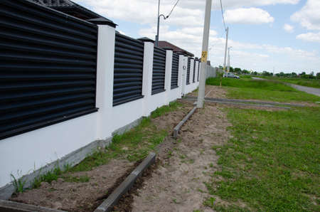Decorative concrete orange fence with brick posts near a residential building with a garden.の写真素材