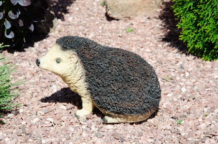 cute garden decor in the form of a hedgehog. Beautiful ceramic figurine of a hedgehog on decorative rubble, summer lawn.の写真素材
