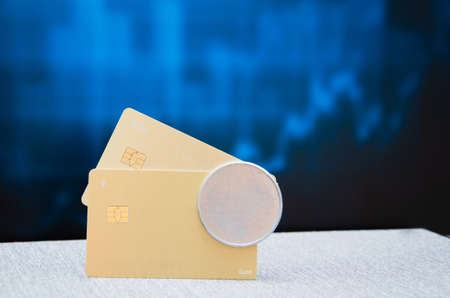A female hand holds a golden plastic bank card on a blurred tile background.の写真素材