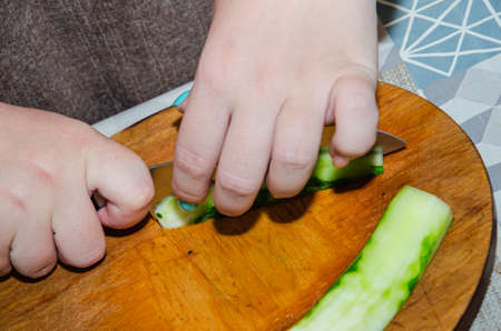 Finely chopping an organic seedless cucumber on a bamboo cutting boardの写真素材