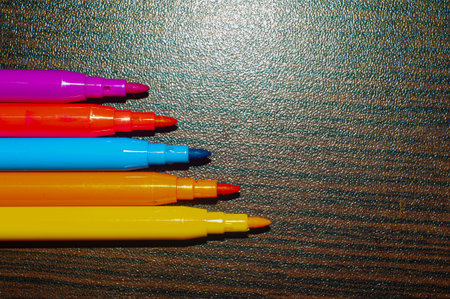 Colored markers in line on black background wood