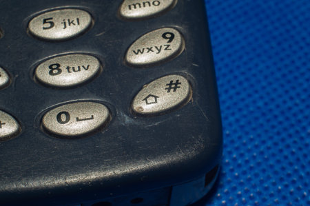 old push-button cell phone on blue background macro