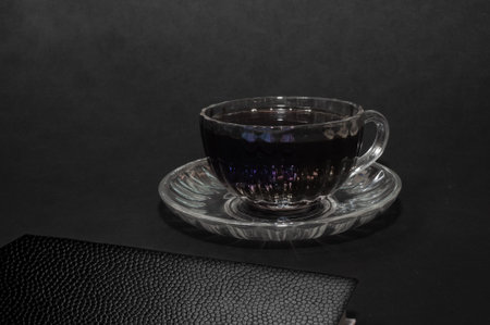 Top view of a cup of coffee and a black leather notebook, isolate on black