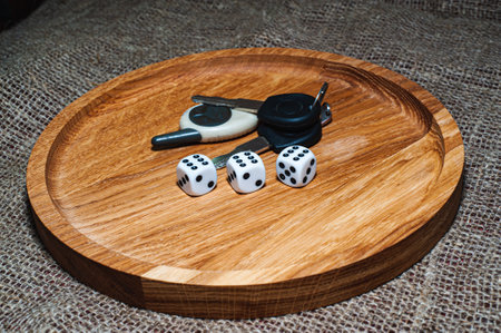 three dice laying over a pile of money on a wooden plate gameの写真素材