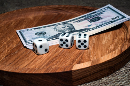 three dice laying over a pile of money on a wooden plate