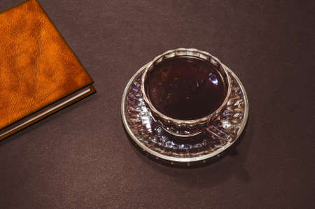 Top view of a cup of coffee and a black leather notebook, isolate on blackの写真素材
