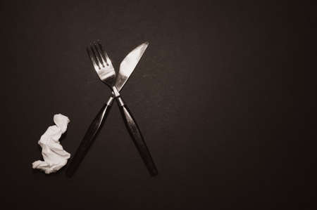 there is a fork with a knife in the form of a cross on a black background. setの写真素材