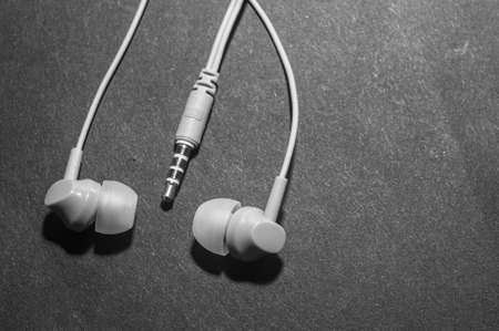 White twisted wired headphones on a monochromatic black surface, close-up. Headset for a mobile phone. musicの写真素材
