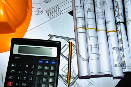 Yellow helmet, house keys and drawing tools on construction plans.の写真素材