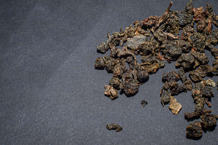 Dry tea with green leaves in wooden spoons, on black backgroundの写真素材