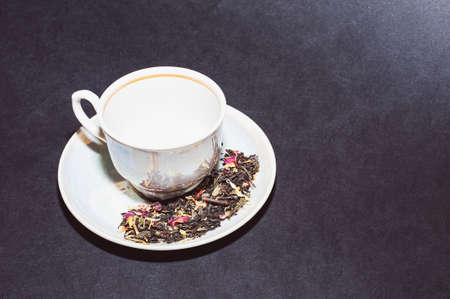 Dry tea with green leaves in spoons, on black backgroundの写真素材