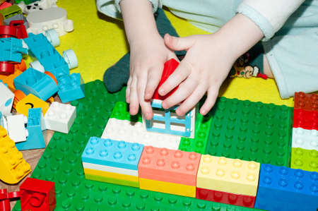 close-up of a child's hand. A 3 year old boy plays with multi-colored building blocks. children's toys, construction.の写真素材
