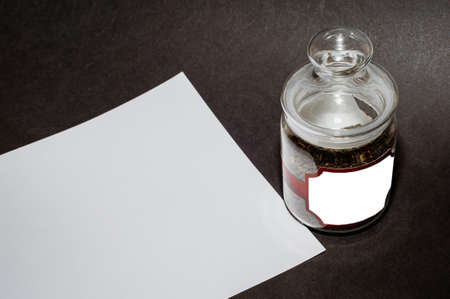 glass jar for tea, on a black background, with a white sheet for writing text.の写真素材