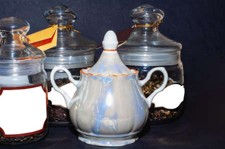 Green tea, a teapot, a cup on a black table, different types of tea in glass jarsの写真素材