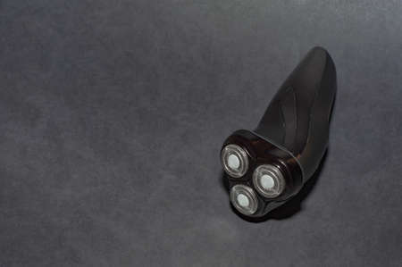 Glossy black electric razor for men on a black background.の写真素材