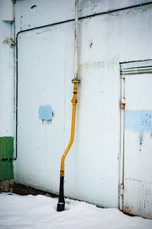 Yellow gas pipe on wall building background. Natural gas for domestic household use, gas pipeline. Gasification of residential houses.の写真素材