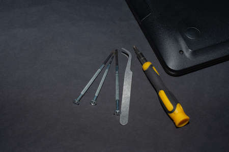 Hands of a computer repairman removing the back cover of the notebook.Computer repair shop. Engineer performing laptop maintenance. Hardware developer fixing electronic components. PC technologyの写真素材